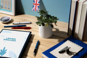 777654 Academia Arabial Andalucía Noticias 24h Desk setup for studying English workbook reading LEARN ENGLISH pens a small succulent in a white pot UK flag and stacked books on a wooden desk